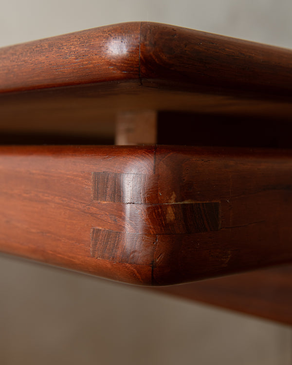 Close-up of a dark reddish-brown wooden table corner showing a mitered joint and wood grain.
